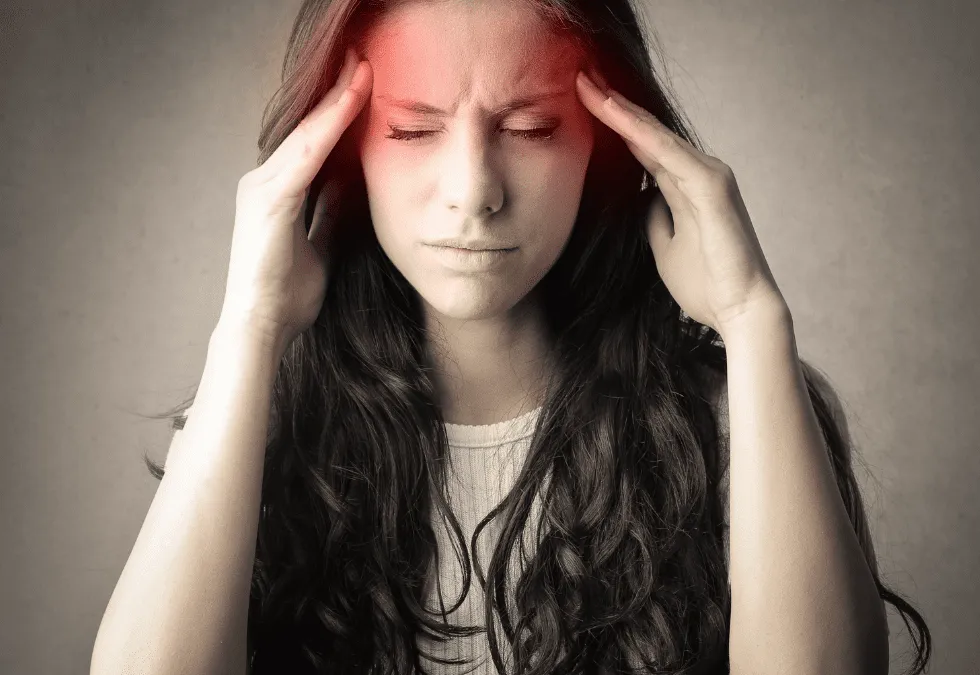 Person holding their head with eyes closed in pain, representing headache discomfort