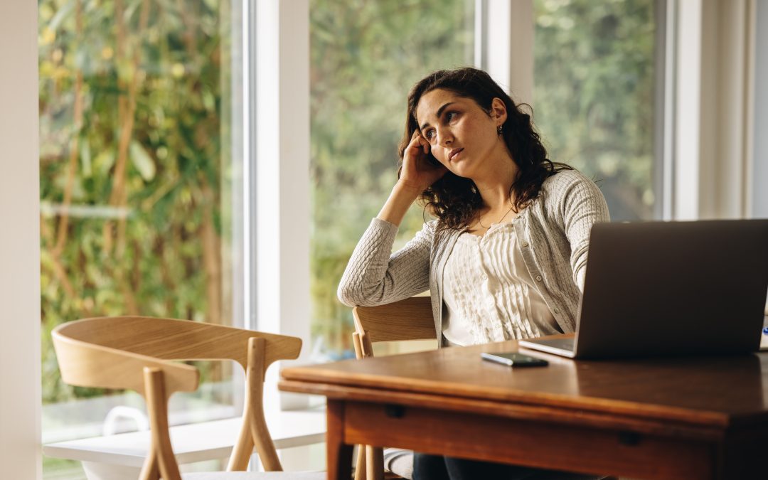 Woman lost in deep thought while working on laptop.