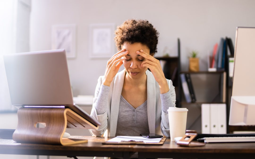A stressed office worker rubbing her temples, experiencing severe brain fog.